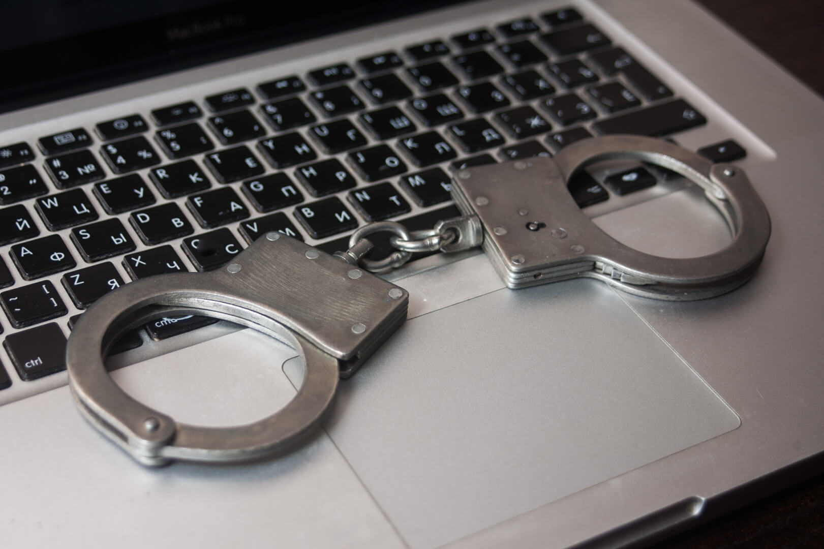 Штраф за мошенничество. Наручники на клавиатуре. Ноутбук и наручники. В наручниках за компьютером.